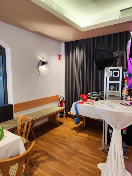 Eck eines Restaurants mit einer Bank, Tischdeko und einem Fernseher an der Wand.