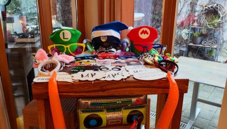 Lustige Hüte, Sonnenbrillen und Accessoires auf einem Tisch, farbenfroh angeordnet.