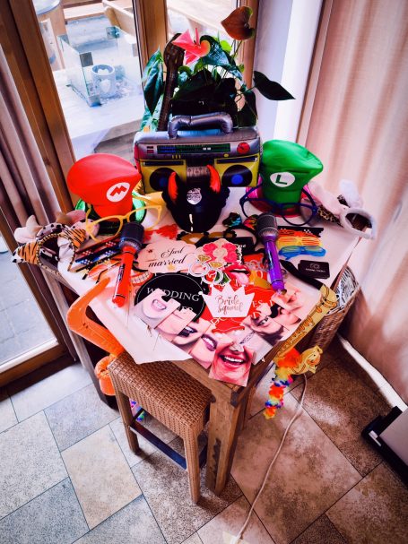 Bunt dekorierter Tisch mit verschiedenen Hüten, Accessoires und farbigen Bildern.