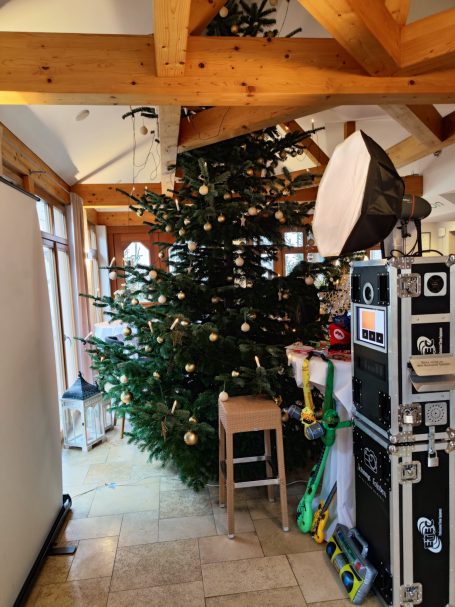 Weihnachtsbaum in einem Raum, umgeben von Dekorationen und einem Studioequipment-Ständer.
