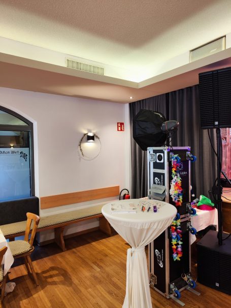 Elegante Eventlocation mit Stehtisch und Dekoration, im Hintergrund technisches Equipment.