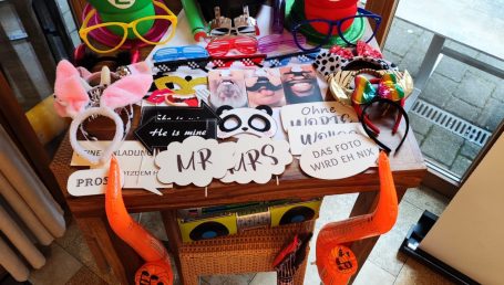 Bunte Kostüme und Accessoires auf einem Tisch, darunter Brillen und Hüte.