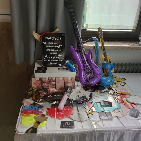 Bunte Musikinstrumente und Partyaccessoires auf einem Tisch, mit einem Werbeplakat.