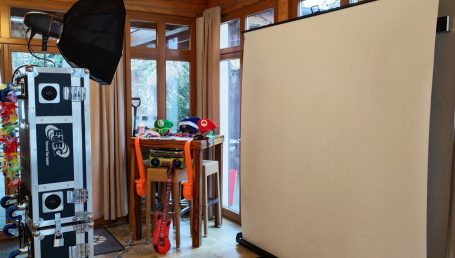 Ein Raum mit Fotohintergrund, Beleuchtung und einem Tisch mit bunten Requisiten.