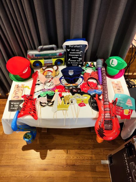 Tisch mit bunten Hüten, Musikinstrumenten und verschiedenen Accessoires.
